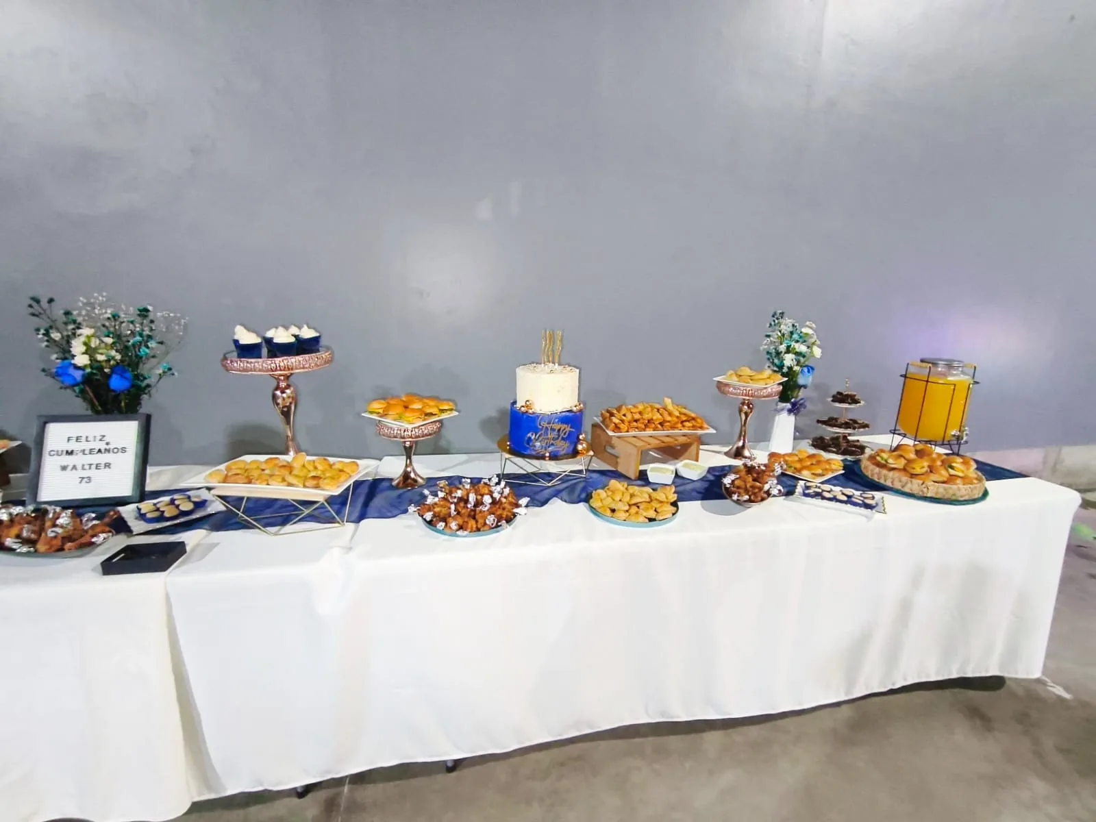 Mesa larga de bocaditos con decoración azul